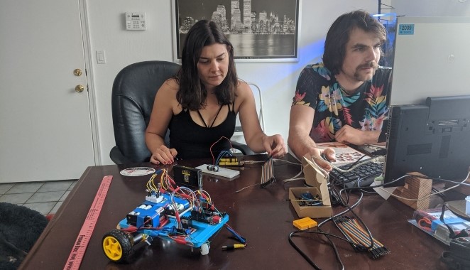 Man and woman working on robot car.