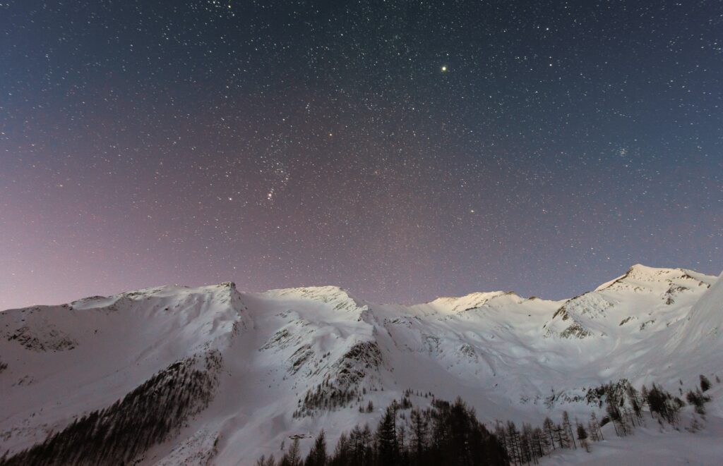 Snowy mountain under starry sky.